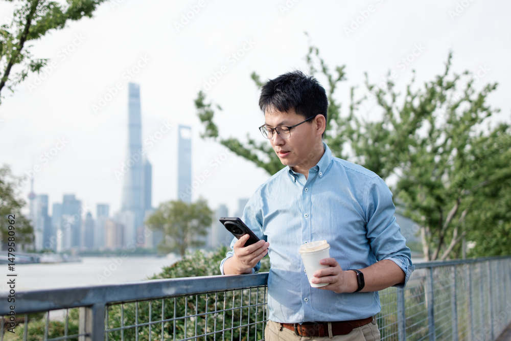 Fototapeta premium asian businessman using smart phone while having coffee