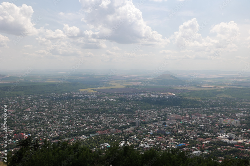 Obraz premium Panoramic Aerial View Of The City Of Pyatigorsk, Russia, Sprawling Below Mount Mashuk. Surrounding Hills And Fields Under A Cloudy Summer Sky. Caucasus Region.
