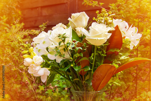 A lush bouquet of fresh white roses and delicate blooms arranged in a glass vase, set against a vibrant green garden backdrop. Perfect for weddings, sympathy, or elegant home decor inspiration
