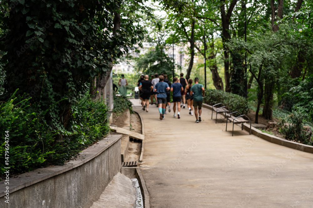 Fototapeta premium Urban running club community in colorful activewear jogging together across pedestrian areas, bridges, and parks. Anonymous group of runners in a vibrant city setting