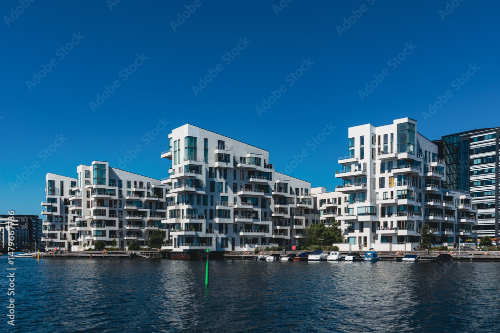 Obraz premium Moderne Wohngebäude am Wasser unter blauem Himmel.