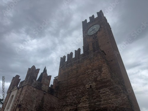 Scaliger castle clock tower looming over borghetto on cloudy day photo