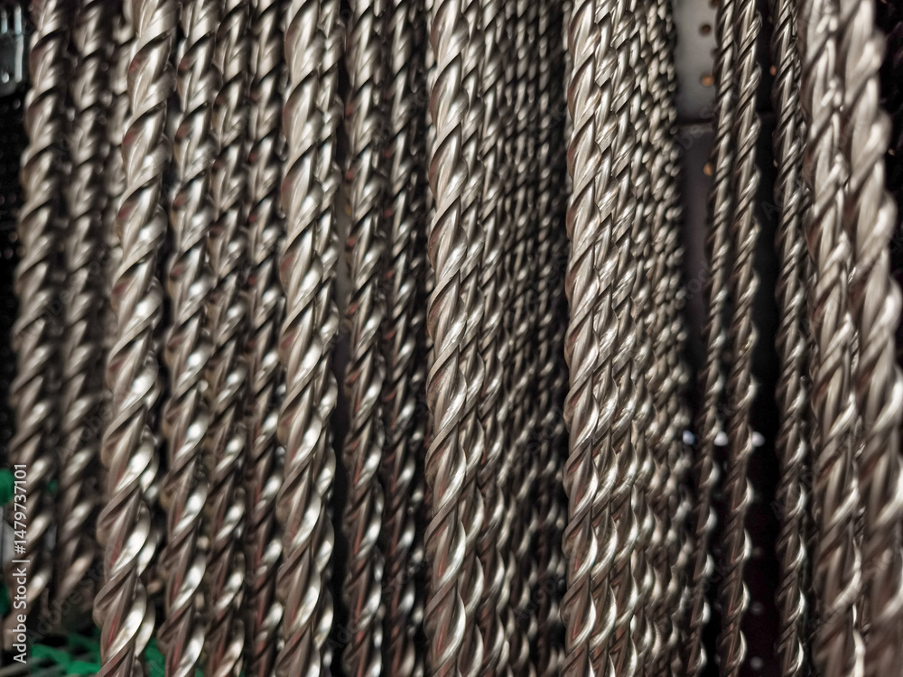 Many identical metal drill bits hanging in a hardware store creating a repetitive pattern Many identical metal drill bits hanging in a hardware store creating a repetitive pattern