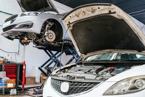 Konstfotografi Two cars getting fixed in auto repair shop with open hoods