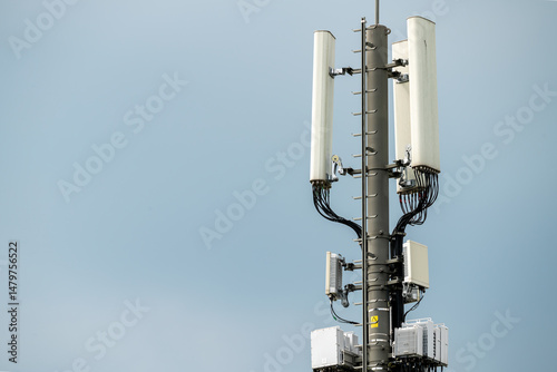 Closeup of antenna array of cellphone mast with aerials and  cabling. Installation. Blue, slightly cloudy sky.