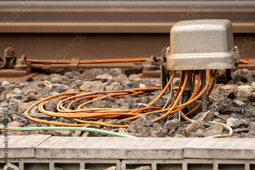 Electrical box besides the reailway track with a bunch of orange cables coming out. Selective focus.