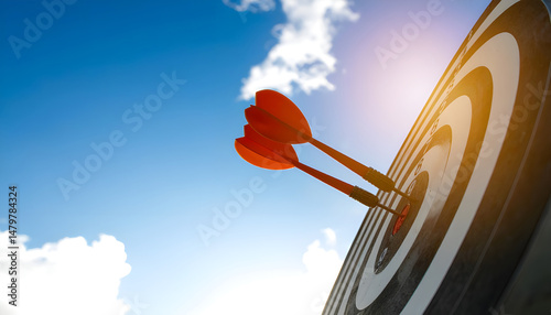 Close up shot red darts arrows in the target center on dark blue sky background. Business target or goal success and winner concept.