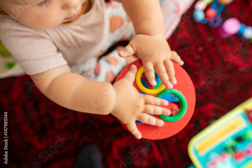 Adorable baby's hands playing with a colorful stacking ring toy. Perfect for developmental milestones and educational content. photo