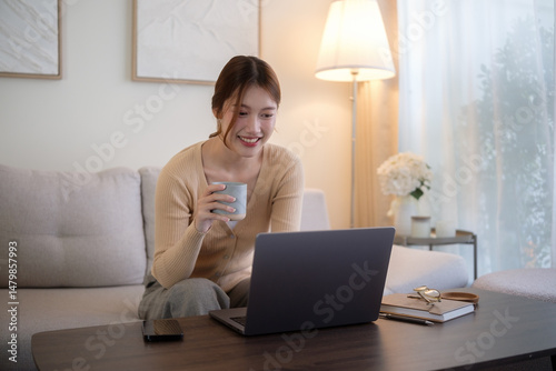 Calm and relaxed moment of a woman working or browsing online from home with a warm drink in hand.