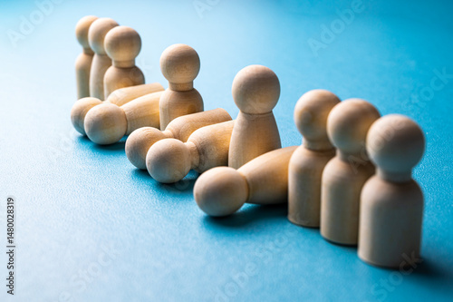 Conceptual representation, with wooden pawns, of corporate layoffs. Concept of layoffs, staff cuts, and mass layoffs.