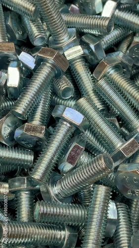 Top-Down View Of A Pile Of Shiny Metal Bolts In Motion, Highlighting Their Use In Industrial Applications And Hardware Design. Vertical.