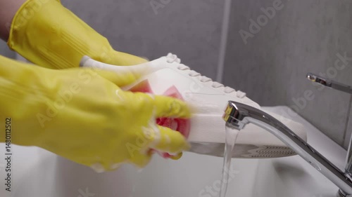 girl washes white shoes by hand in closet