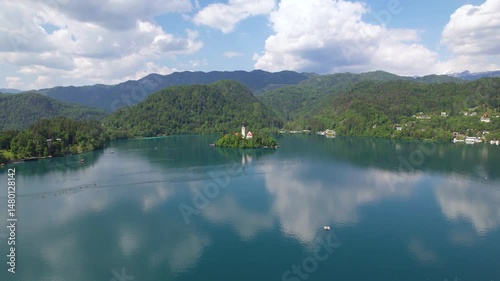 Aerial view of Church of the Assumption of Mary in the center of the lake Bled. Flying around small island on Bled Lake in Slovenia, warm summer day sun