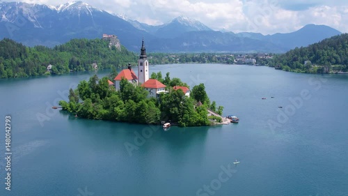 Aerial view of Church of the Assumption of Mary in the center of the lake Bled. Flying around small island on Bled Lake in Slovenia, warm summer day sun