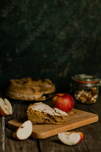 Traditional apple pie Charlotte apples are lying nearby. Sweet Thanksgiving dinner, autumn seasonal apple pie sliced one piece on wooden tray, on dark wooden background.