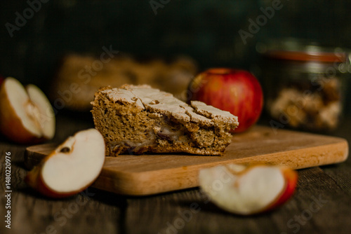 Traditional apple pie Charlotte apples are lying nearby. Sweet Thanksgiving dinner, autumn seasonal apple pie sliced one piece on wooden tray, on dark wooden background.