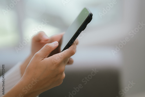 Close-up of a young woman's hand holding a smartphone and chatting on social media.