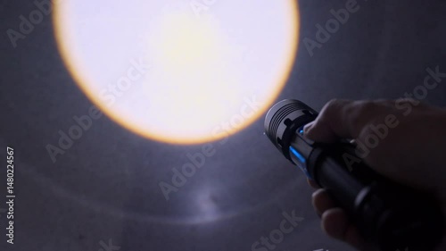 In an unlit home, a person turns on a handheld flashlight, partially lighting the surroundings. A perfect clip to represent uncertainty or indoor exploration