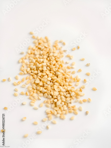 A close-up of raw sesame seeds scattered across a clean white background