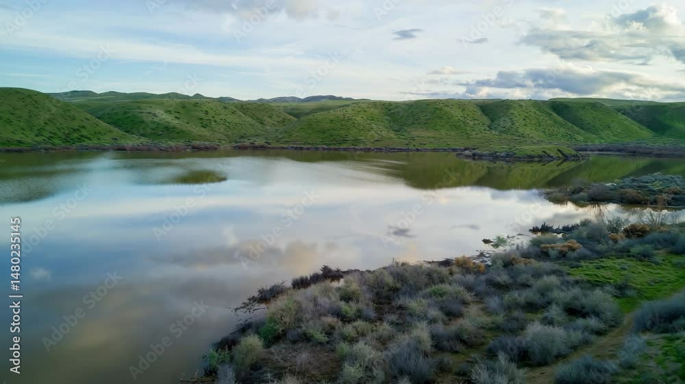 Drone Shot of Calm Lake Water Reflecting Green Hills and Sky Drone Shot of Calm Lake Water Reflecting Green Hills and Sky