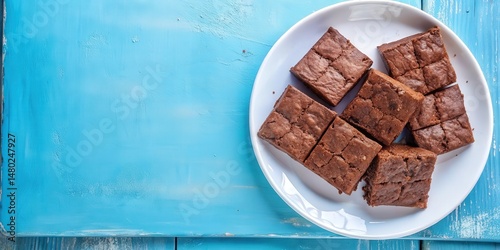 A plate of freshly baked brownies sits on a rustic blue background, ready to be enjoyed.