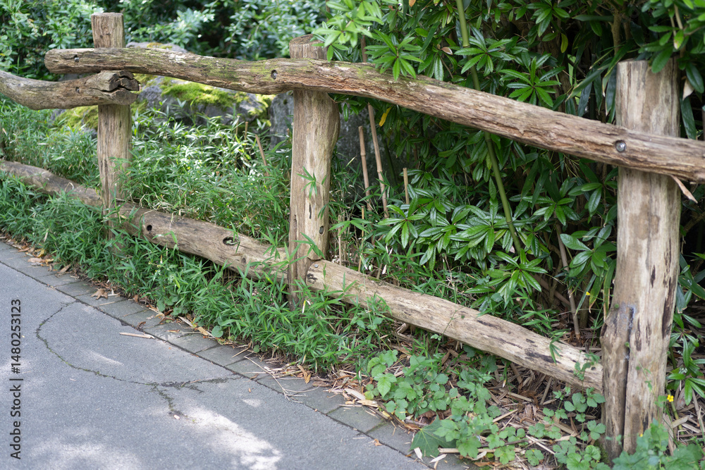 Fototapeta premium Old weather-worn wooden log fence in a summer rural area