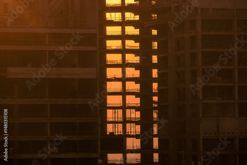 Construction site on sunset. Tower cranes in action. Housing building and real estate. Crane during formworks. 