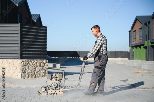 фотографія Landscaping worker using vibratory tamping machine plate compactor on a new pati