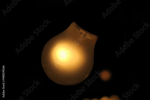 Ampoule électrique allumée sur fond sombre.