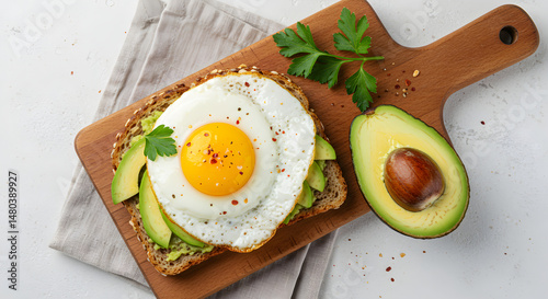 Healthy Avocado Toast With Fried Egg Served on Wooden Board Top View