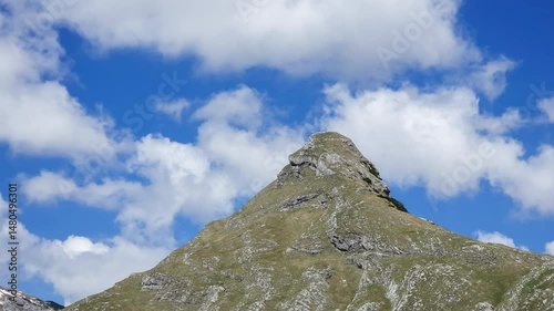 Mountain peak - top of the hill time lapse. Bare rock pointing upward geological formation with fast moving clouds in the sky. Stožina Durmitor national park in Montenegro hyper lapse.