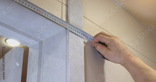 Construction worker measuring door frame with tape measure