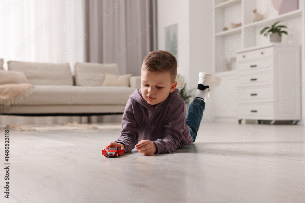 Naklejka premium Little boy playing with toy car at home