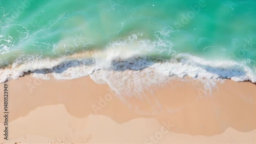 Aerial view of turquoise ocean waves breaking on sandy beach  