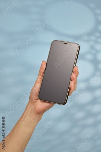 woman holding smartphone with blank screen on blue background
