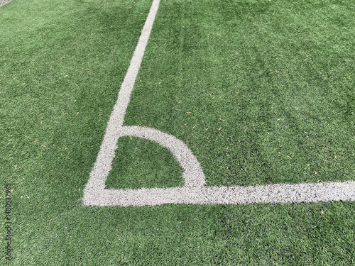 Corner kick spot or corner area. Artificial turf on a football field with a fragment of white marking lines. Soccer pitch surface.