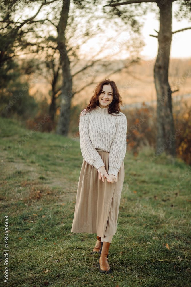 Smiling woman enjoying autumn day in nature wearing sweater and skirt Smiling woman enjoying autumn day in nature wearing sweater and skirt