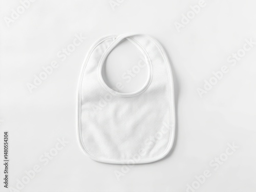 White Baby Bib Mockup. A simple white bib laid on a light background, ideal for baby feeding.