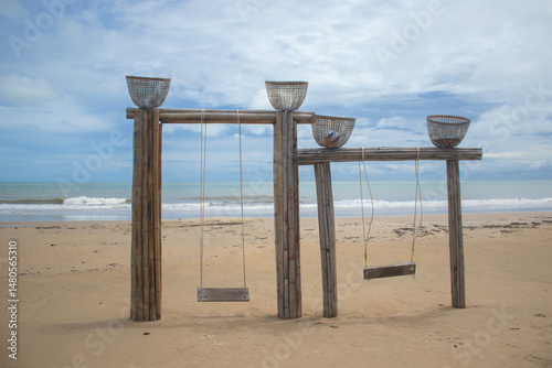A wooden swing has been built on the sandy beach by the sea at tourist spots.