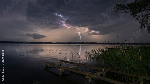 Lightning storm over lake and wooden pier in Masuria, Poland.