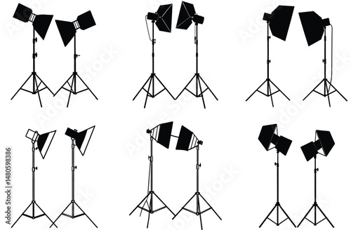 A black silhouette of a photographer with a camera on a tripod stands in a studio with professional lighting equipment