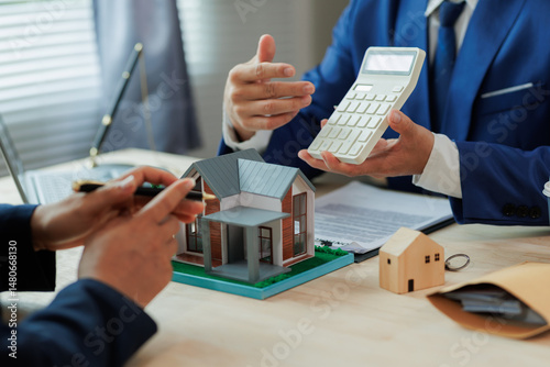A real estate agent assists a client by calculating mortgage rates and monthly payments, helping them understand their home financing options.