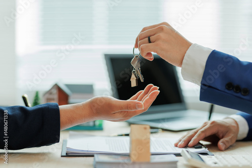 Obraz na płótnie Client pays the agent, who hands over the house keys, marking the official closing and completion of the real estate transaction. w salonie