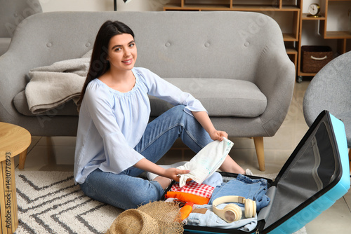 Young woman packing clothes...