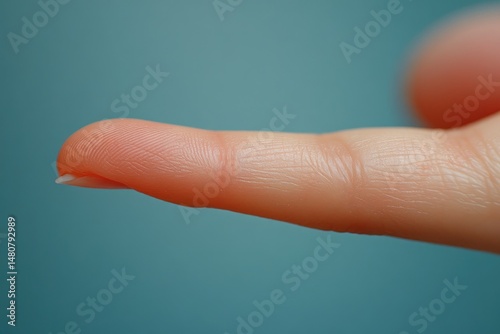 Close up image of an extended human finger against a blue background