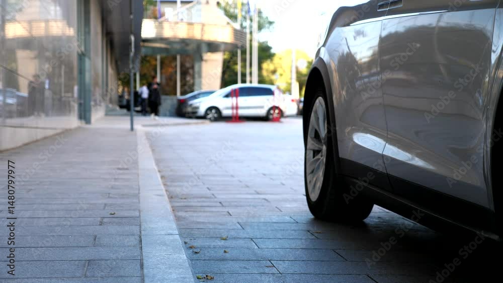 Male driver coming to electric car and open door for businesswoman. Chauffeur uncover door of modern vehicle for female passenger. Elegant business woman get out from auto and walk to office building