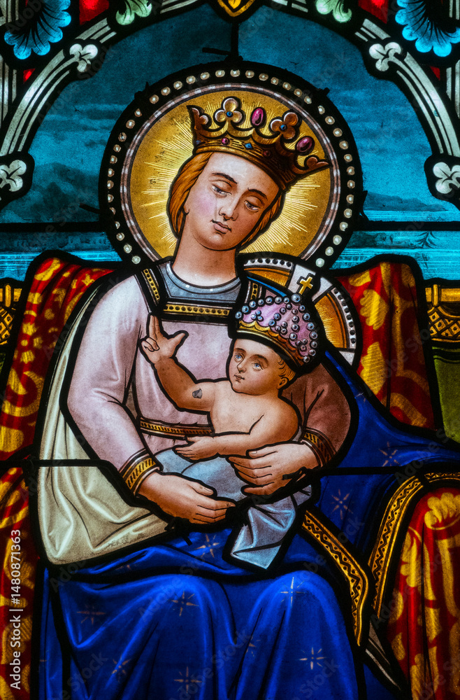 Fototapeta premium Stained glass (1913) of Blessed Virgin Mary holding baby Jesus Christ in her arms.