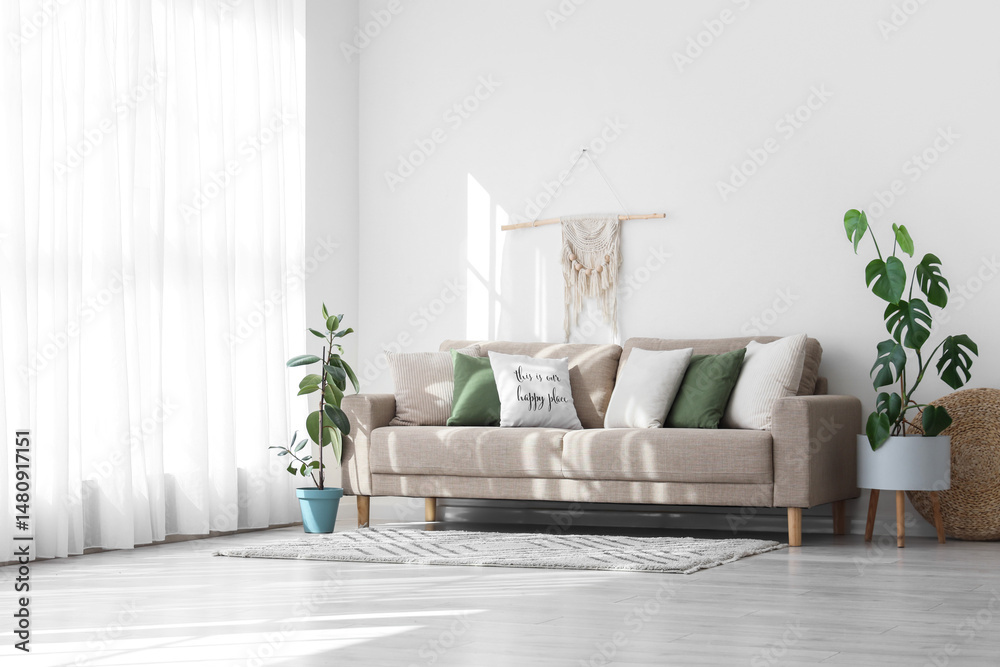 Obraz premium Interior of light living room with cushions on grey sofa and plants