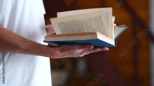 A woman in a white T-shirt flips through and reads a close-up blue book. High quality FullHD footage