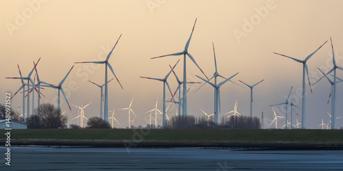 Windräder bei Wesselburenerkoog an der Eidermündung an der Nordsee in Dithmarschen, Schleswig-Holstein. Windräder vorne im Schatten, hintere im Abendlicht